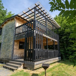Cabane moderne en bois avec terrasse en verre, entourée de verdure à Limousin.