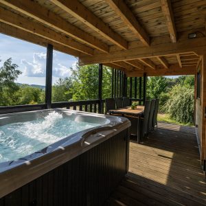 Cabane en bois avec jacuzzi, offrant une vue dégagée sur la nature verdoyante.