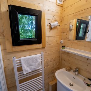 Salle de bain en bois dans un hébergement insolite à Limousin, avec fenêtre vue nature.