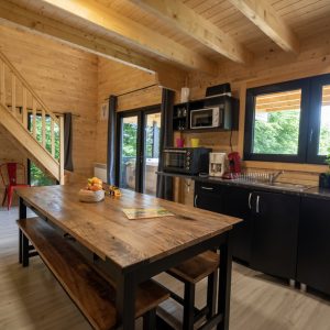 Cabane en bois à Limousin avec cuisine moderne et grande table en bois.