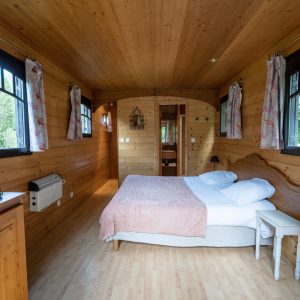 Chalet en bois chaleureux avec lit douillet et fenêtres lumineuses dans le Limousin.