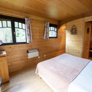 Chalet en bois cosy à Limousin, avec lit douillet et fenêtres lumineuses.