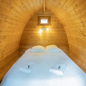 Cabane en bois au Limousin, intérieur chaleureux avec lit douillet et lumière apaisante.