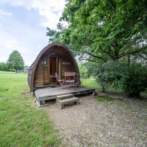 Cabane en bois en forme de dôme, avec une terrasse et un cadre verdoyant.