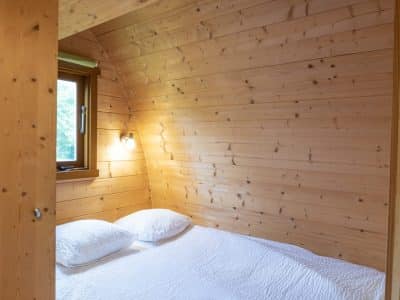 Cabane en bois cosy à Limousin, avec lit douillet et lumière naturelle.
