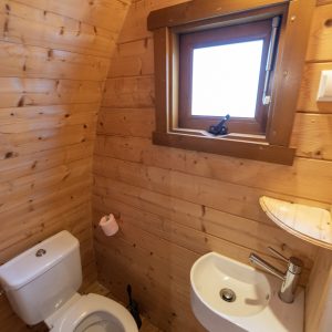 Toilettes en bois dans un hébergement insolite à Limousin, avec fenêtre lumineuse.