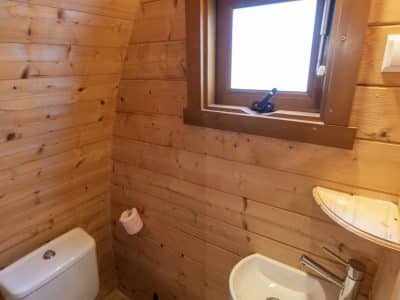 Toilettes en bois dans un hébergement insolite à Limousin, avec fenêtre lumineuse.
