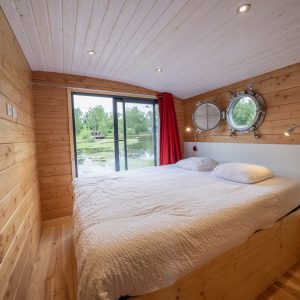 Cabane en bois avec vue sur leau, lit confortable et ambiance chaleureuse.