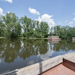 Hébergement insolite en Auvergne : maisons flottantes sur un lac paisible, entourées darbres.