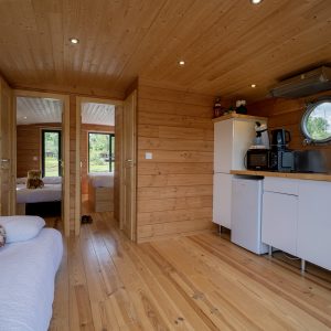 Cabane en bois en Auvergne, intérieur chaleureux avec cuisine et lits confortables.