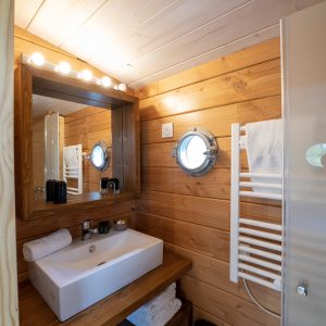 Salle de bain en bois dun hébergement insolite à Limousin, avec miroir lumineux.