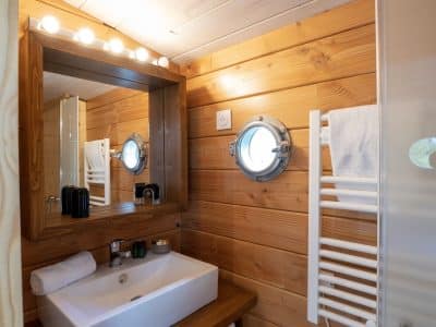 Salle de bain en bois dun hébergement insolite à Limousin, avec miroir lumineux.