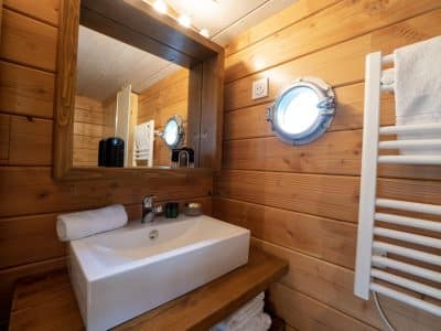 Salle de bain dun hébergement insolite en Auvergne, avec un miroir rond et bois chaleureux.