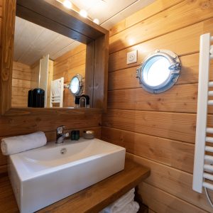 Salle de bain en bois dans un hébergement insolite à Limousin, avec miroir rond.