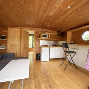 Intérieur chaleureux dun hébergement insolite en Limousin, avec bois et cuisine équipée.