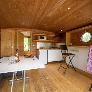Hébergement insolite en Auvergne : intérieur en bois chaleureux avec cuisine équipée.