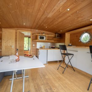 Hébergement insolite en Auvergne : intérieur en bois chaleureux avec kitchenette moderne.
