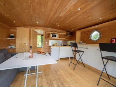 Hébergement insolite en Auvergne : intérieur en bois chaleureux avec kitchenette moderne.