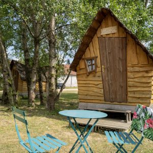Cabane en bois typique en Auvergne, avec chaises et table en extérieur.