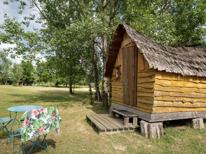 Cabane en bois typique en Auvergne, entourée dun espace verdoyant et dune table colorée.