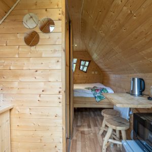 Cabane en bois à Champagne-Ardenne, intérieur chaleureux avec kitchenette et lit douillet.