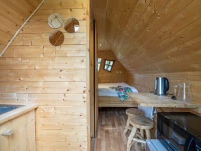Cabane en bois à Champagne-Ardenne, intérieur chaleureux avec kitchenette et lit douillet.