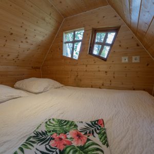 Cabane en bois cosy à Champagne-Ardenne, avec fenêtres originales et lit douillet.