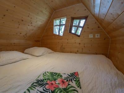 Cabane en bois cosy à Champagne-Ardenne, avec fenêtres originales et lit douillet.