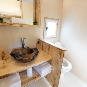 Salle de bain dun hébergement insolite en bois, avec lavabo en pierre naturelle.