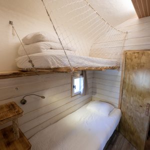 Hébergement insolite en Auvergne : chambre cosy avec lit suspendu et décor en bois.