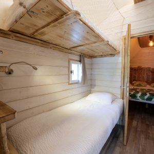 Chalet en bois cosy à Limousin, avec lit simple et lumière chaleureuse.