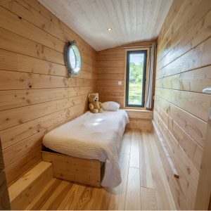 Cabane en bois à Auvergne, avec un lit simple et une vue sur la nature.