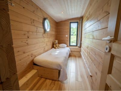 Cabane en bois à Auvergne, avec un lit simple et une vue sur la nature.