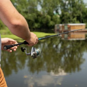 Hébergement insolite en Auvergne : maison flottante au bord dun lac, pêcheur à lœuvre.