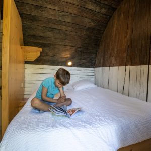 Cabane en bois en Auvergne, un enfant lit sur un lit douillet.