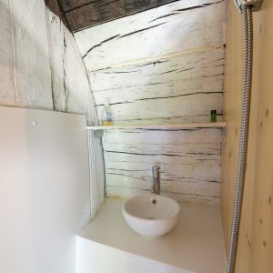 Douche moderne dans un hébergement insolite en Auvergne, ambiance boisée et chaleureuse.