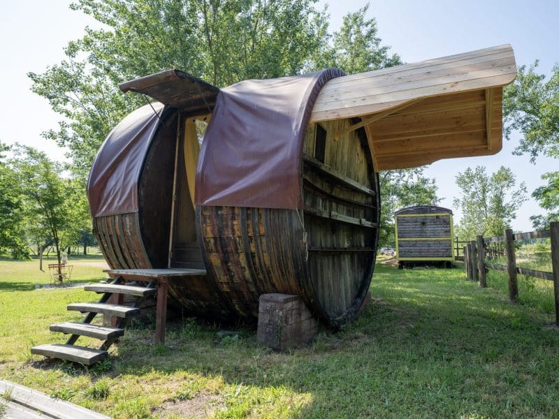 Hébergement insolite en Auvergne : cabane en forme de tonneau avec terrasse en bois.