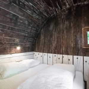 Hébergement insolite en Auvergne : cabane en bois avec lit confortable et fenêtre.