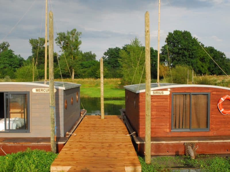 Hébergement insolite en Auvergne : maisons flottantes colorées sur un ponton en bois.