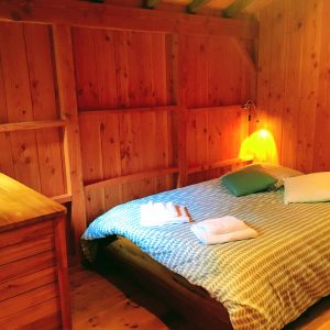 Chalet en bois chaleureux avec lit douillet et lumière tamisée.