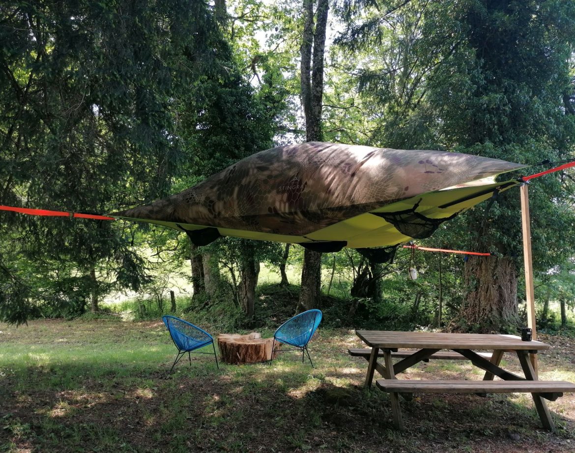 Hébergement insolite en Auvergne-Rhône-Alpes : tente suspendue au milieu des arbres.