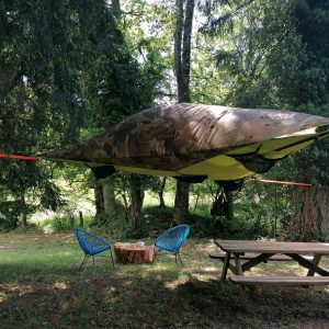 Hébergement insolite en Auvergne-Rhône-Alpes : tente suspendue au milieu des arbres.