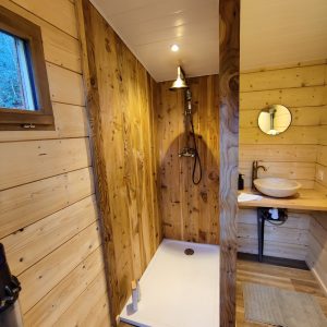 Douche en bois dans un hébergement insolite en Midi-Pyrénées, ambiance chaleureuse.