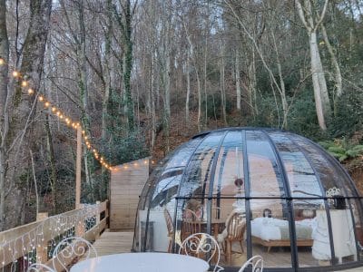 Hébergement insolite en bulle transparente, entouré de nature et décoré de guirlandes lumineuses.