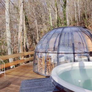 Hébergement insolite en Midi-Pyrénées : bulle transparente avec jacuzzi et vue sur la forêt.