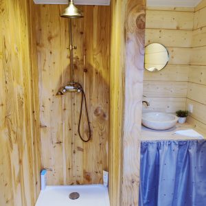 Douche en bois dans un hébergement insolite en Midi-Pyrénées, ambiance chaleureuse.