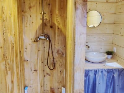 Douche en bois dans un hébergement insolite en Midi-Pyrénées, ambiance chaleureuse.