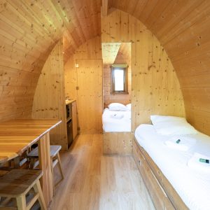 Hébergement insolite en forme de cabane en bois, intérieur chaleureux et lumineux.