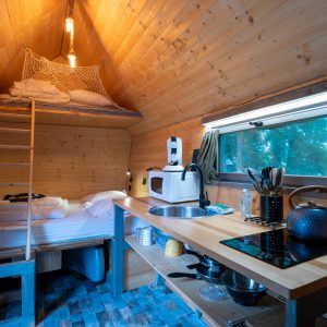 Cabane en bois cosy avec mezzanine et cuisine équipée, idéale pour un séjour nature.