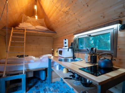 Cabane en bois cosy avec mezzanine et cuisine équipée, idéale pour un séjour nature.